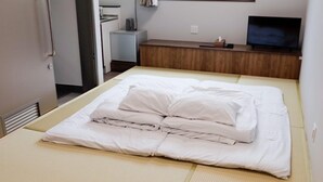 A neatly made bed with white bedding and a wooden headboard. - HOTEL KANALOA (Tokashiki)