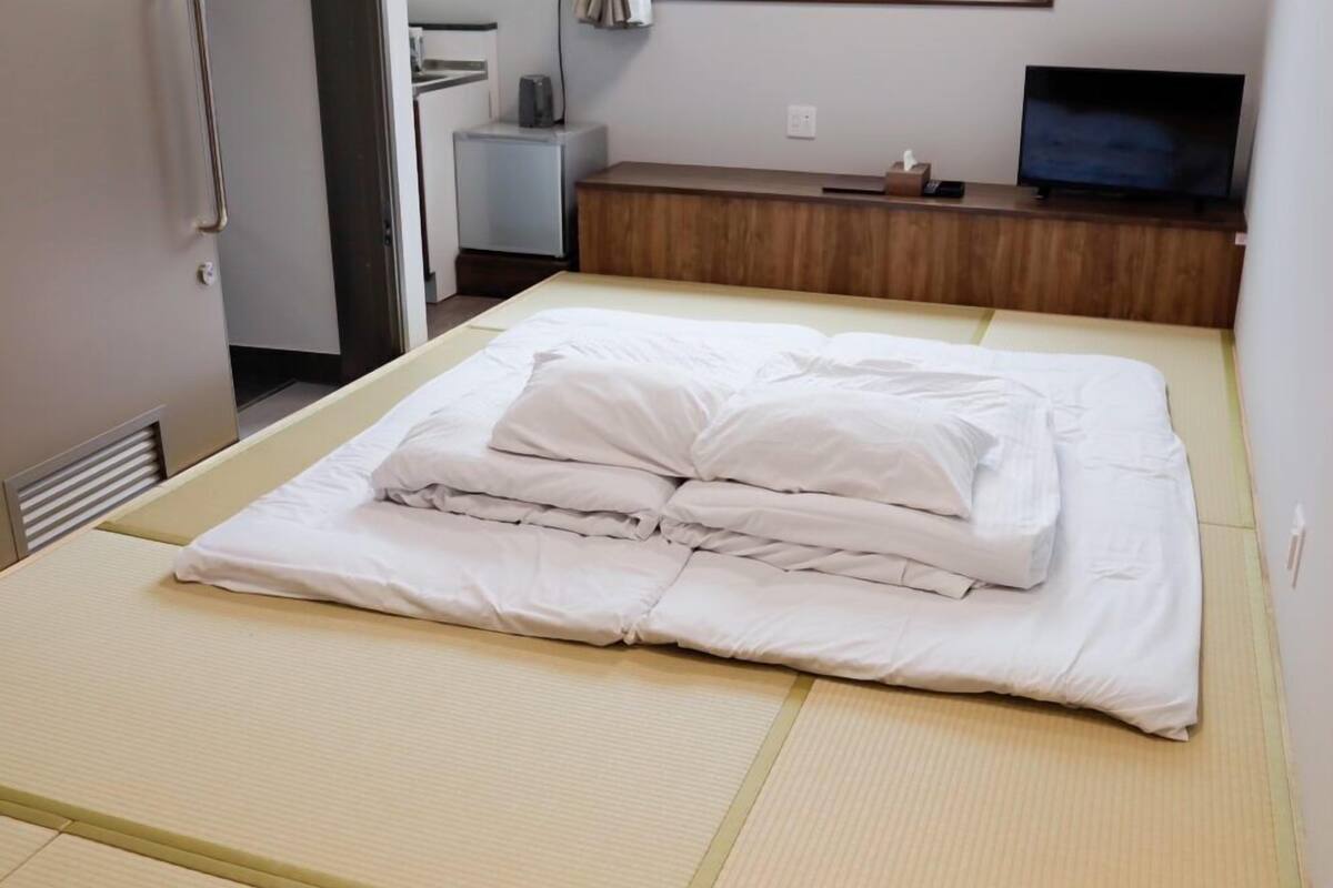 Una cama bien hecha con ropa blanca y cabecera de madera.