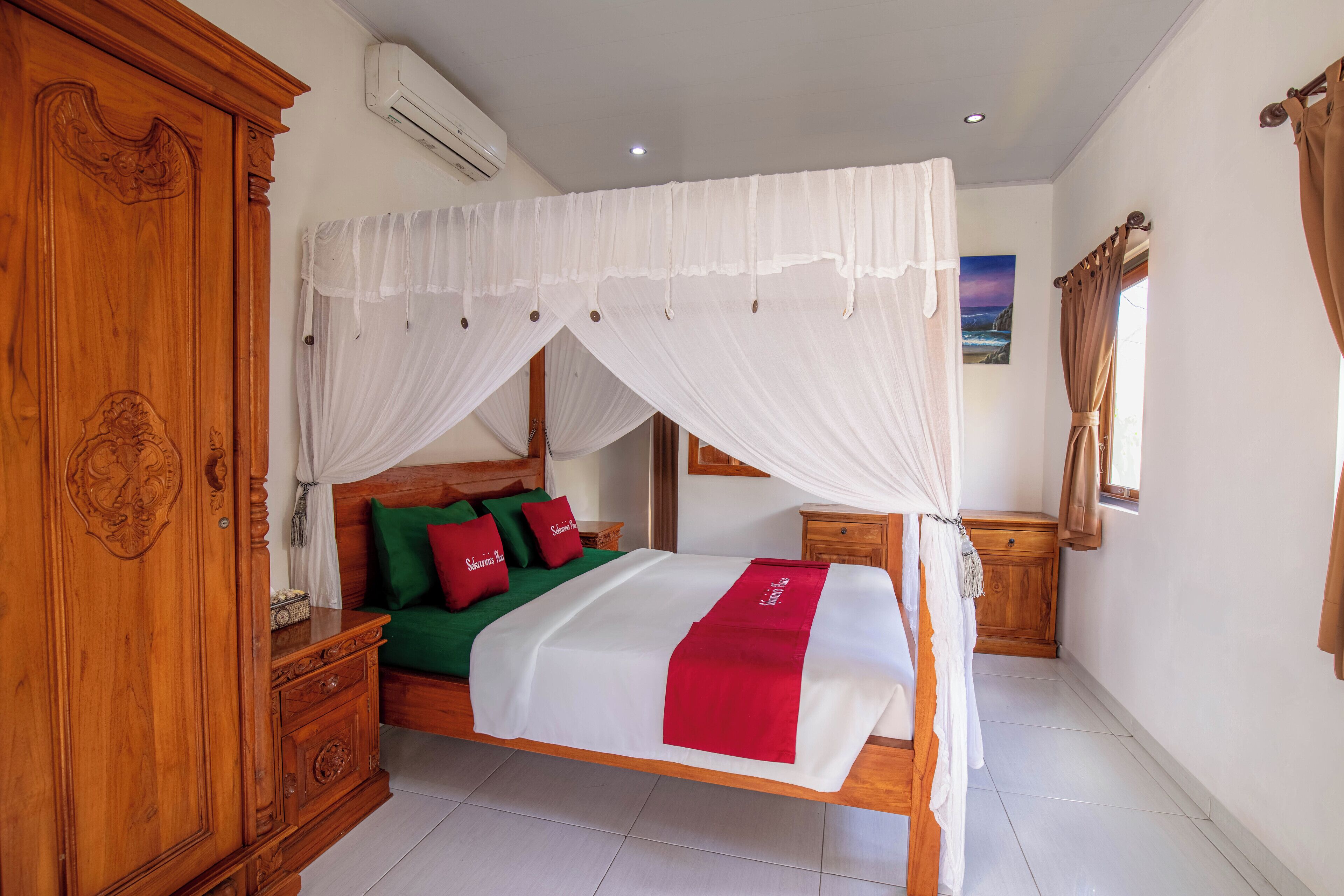 A four-poster canopy bed with a white bedspread and red accents, a wooden wardrobe, and a nightstand with a lamp.