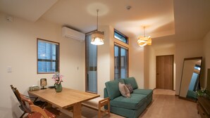 Uma sala de estar moderna com uma mesa de jantar de madeira, um sofá verde e uma cadeira de madeira.