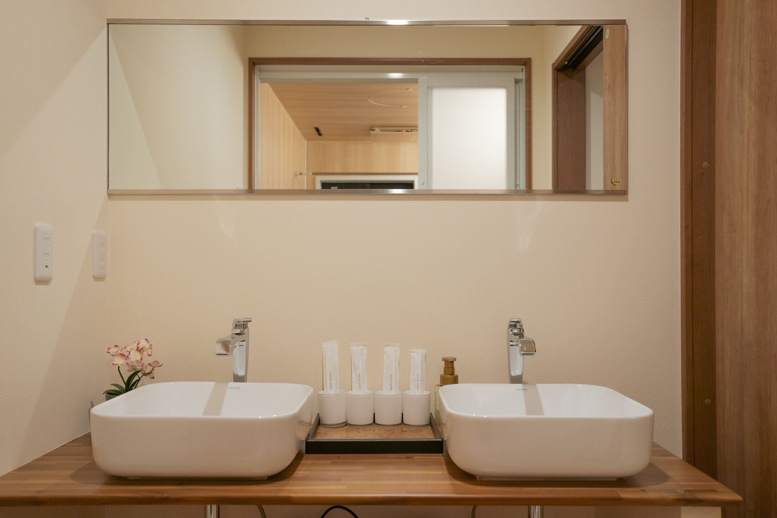 Een badkamer met twee witte wasbakken, een spiegel erboven en een houten aanrechtblad.