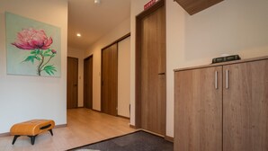 Um corredor com portas de madeira, um banco e um quadro de uma flor.