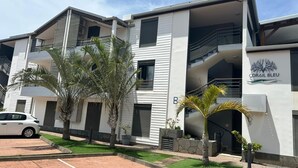Un immeuble à plusieurs étages doté de balcons et d’un espace de stationnement.
