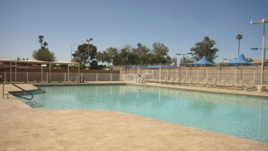 A swimming pool with a tiled deck, sun loungers, and umbrellas. - Cozy 1-bedroom condo resort in charming Mesa with WiFi, AC (Mesa)