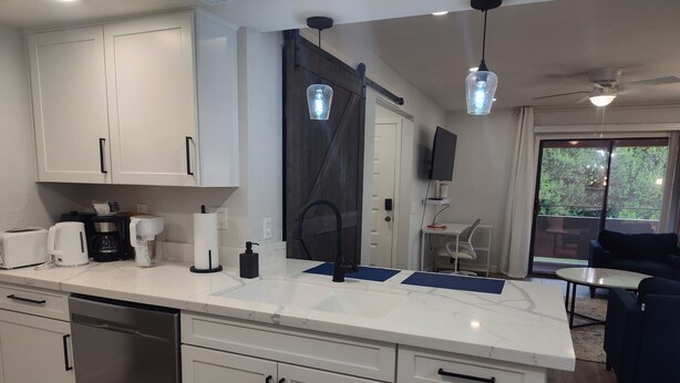 A modern kitchen with white cabinetry, a dishwasher, a coffee maker, and a sink. - Cozy 1-bedroom condo resort in charming Mesa with WiFi, AC (Mesa)
