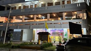 A multi-story building with balconies, a flag, and a parked car. - Banyantree Samudra (Kovalam)