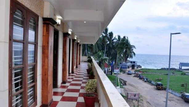 A hotel corridor with checkered flooring, wooden columns, and large windows. - Banyantree Samudra (Kovalam)