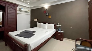 A hotel room with a bed, bedside table, nightstand, and a ceiling fan. - Banyantree Samudra (Kovalam)