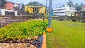 A landscaped area with a water feature, a yellow building, and a white building in the background. - Banyantree Samudra (Kovalam)