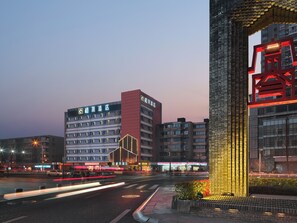 Ein mehrstöckiges Hotel mit auffälliger Beschilderung, ein modernes Gebäude mit einer markanten Fassade und eine gut beleuchtete Straße bei Nacht.