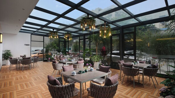 A spacious indoor area with a wooden floor, multiple tables and chairs, and large windows allowing natural light. - chengduchengguojiudian (Chengdu)
