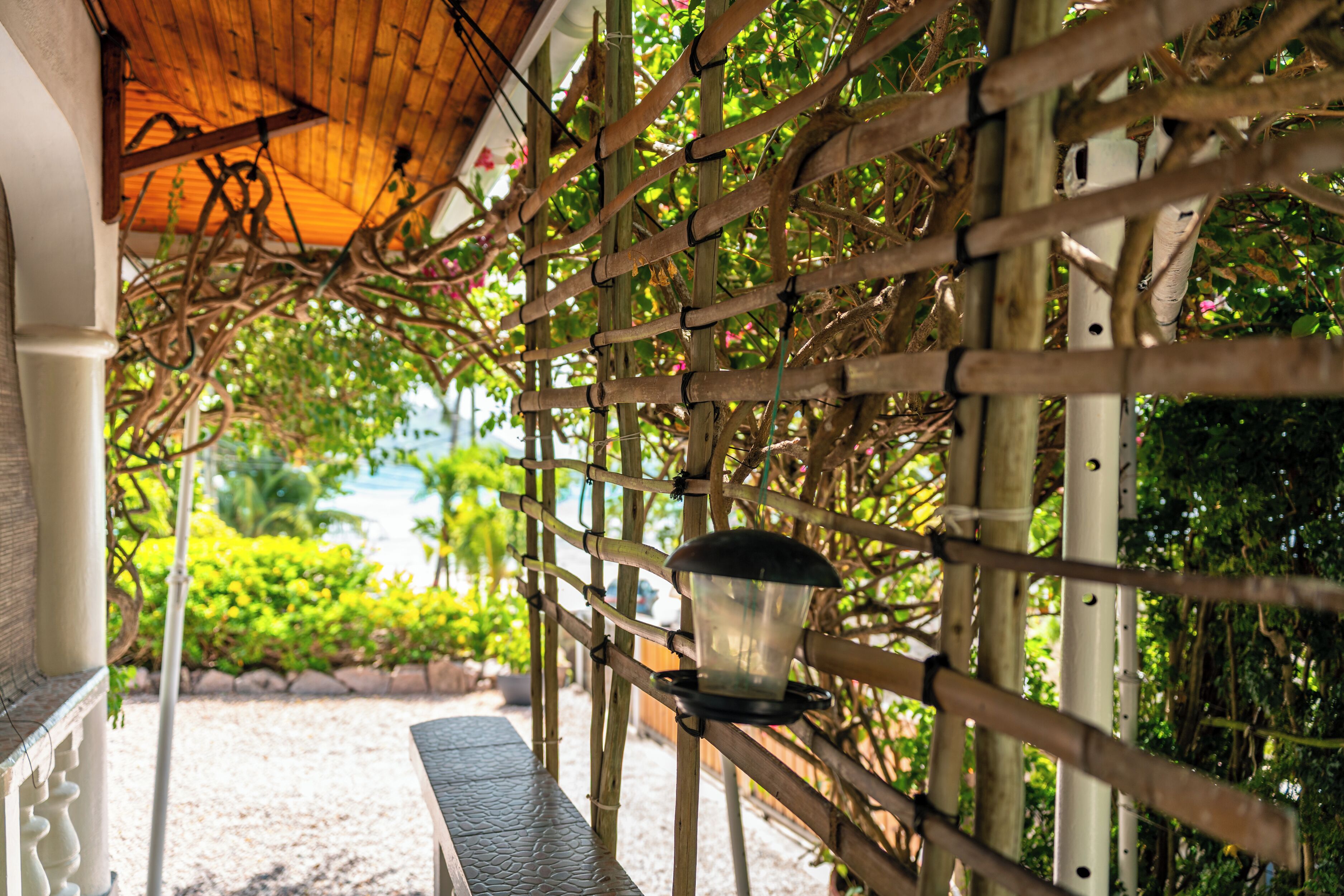 A covered outdoor area with a bamboo fence, a bench, and a hanging lantern.