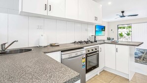 Eine moderne Küche mit weißen Schränken, einer Granit Arbeitsplatte, einem Gasherd und einem eingebauten Backofen.