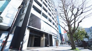A modern building with a glass facade, a visible entrance, and a tree in front. - HIT Tenjin (Fukuoka)