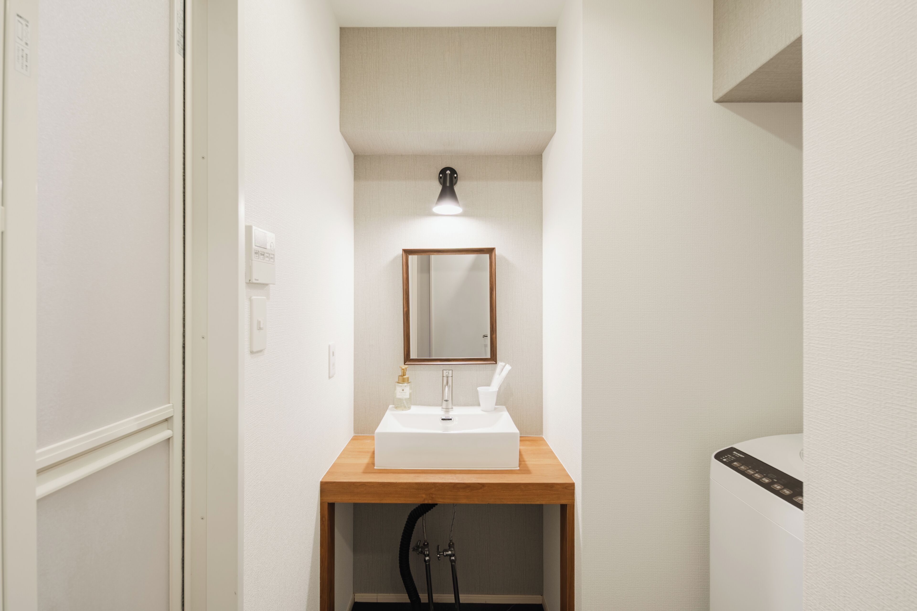 A bathroom with a white sink, a mirror, and a light fixture above the mirror.