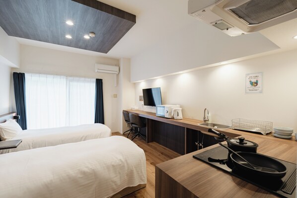 A hotel room with two beds, a kitchenette, a desk, and a large window with curtains. - HIT Tenjin (Fukuoka)