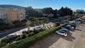 A parking lot with several cars, a road with a few vehicles, and buildings in the background.