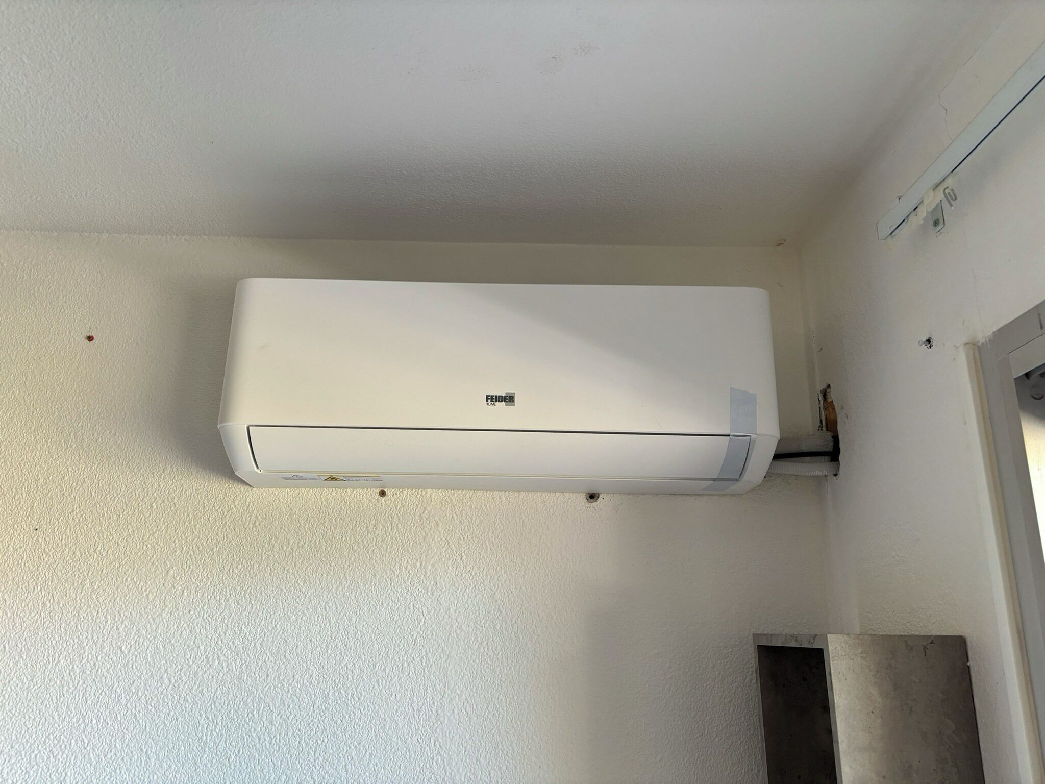 Un aparell de condicionament de l'aire blanc fixat a una paret amb relleu.