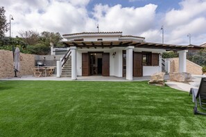 A modern house with a patio, stone walls, and a well-maintained lawn.