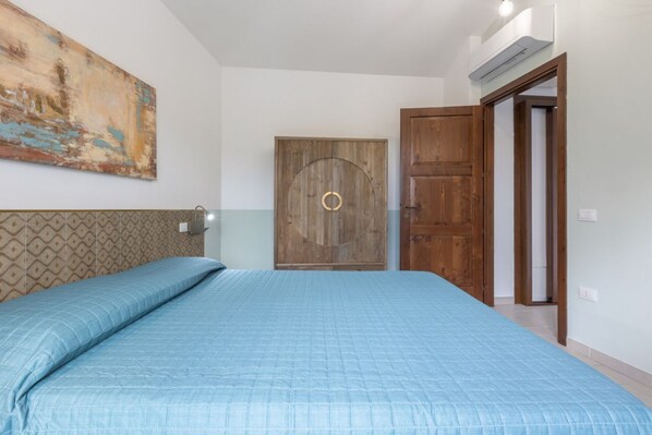 Un dormitorio con una cama, una puerta de madera y un cuadro en la pared.