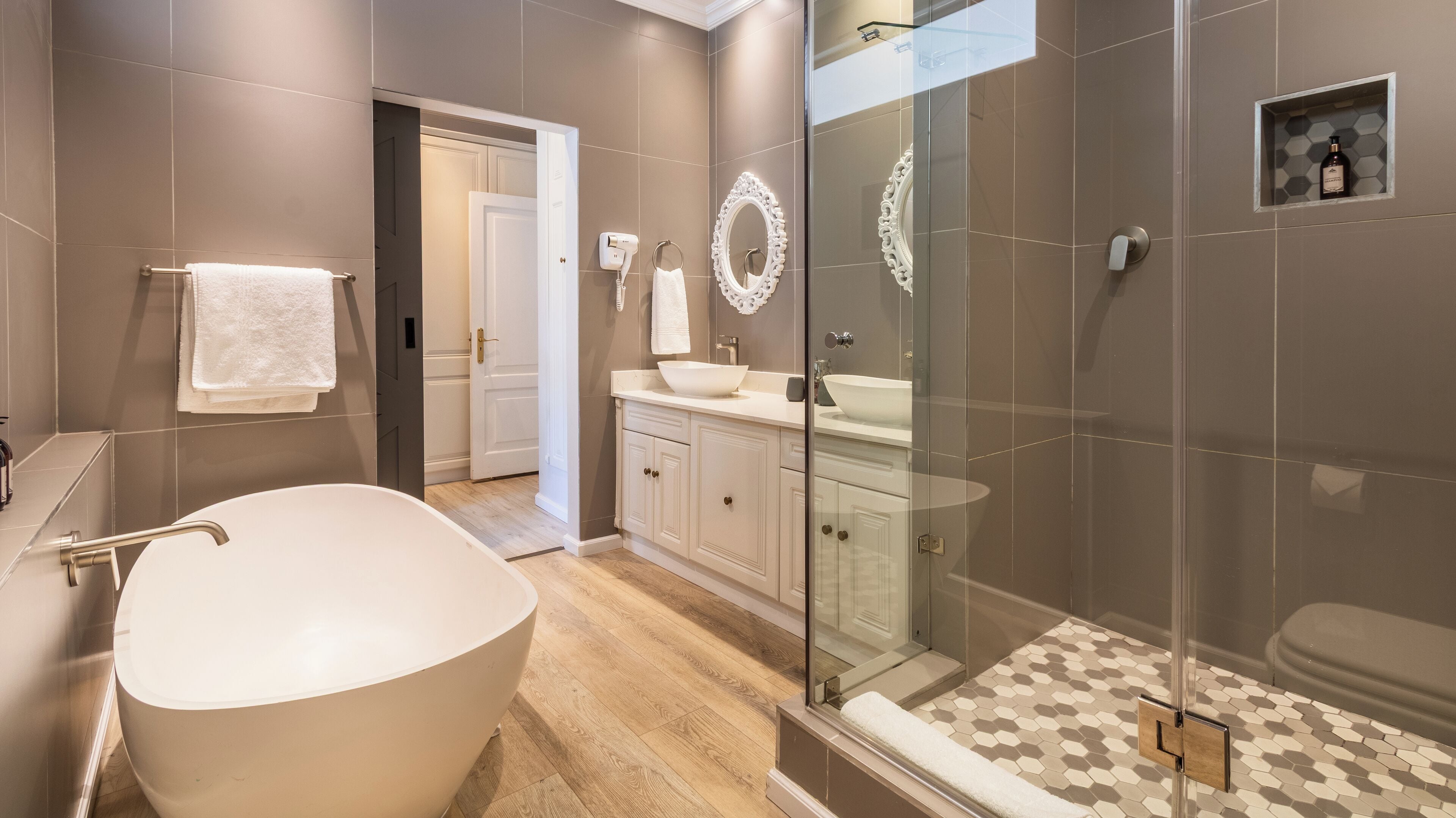 Une salle de bain moderne avec une baignoire sur pieds, une douche à parois de verre et un meuble-lavabo doté d’un grand miroir.
