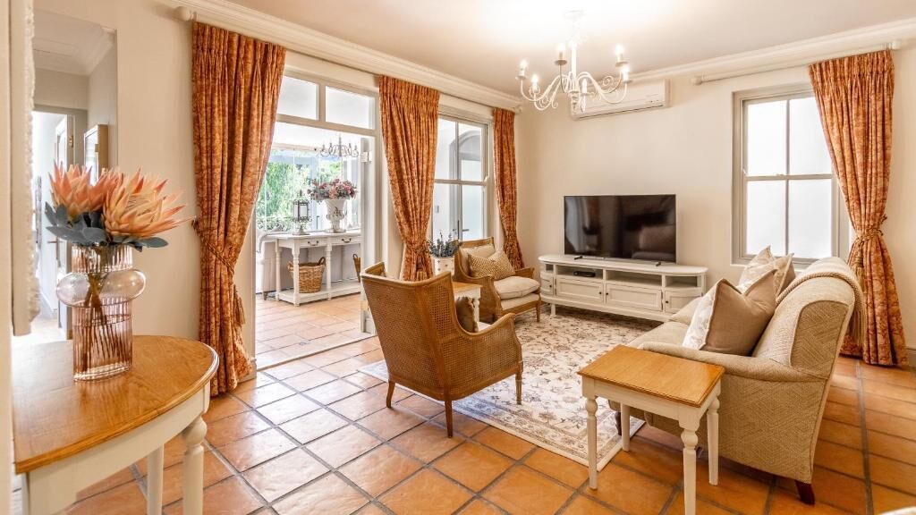 A living room with a sofa, armchair, TV, and a dining area with a table and chairs.