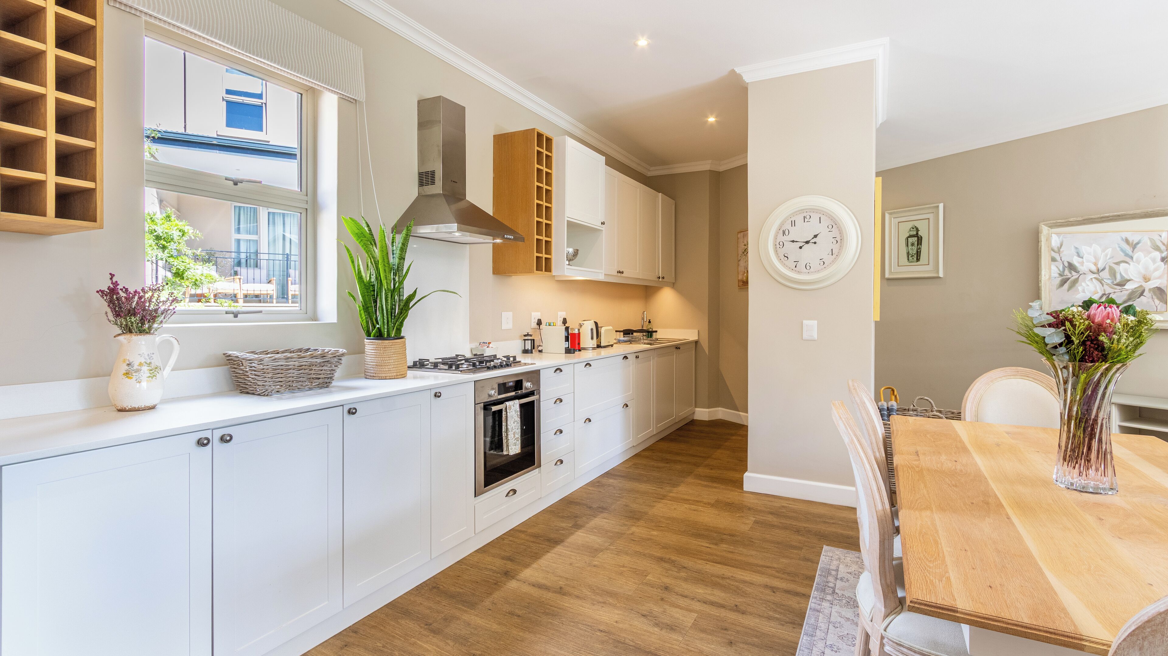 A modern kitchen with white cabinets, a built-in oven, and a large window.