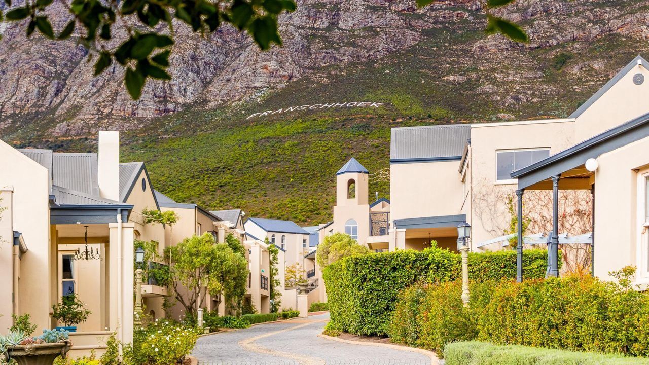 A residential street with houses, a church, and a mountain in the background.