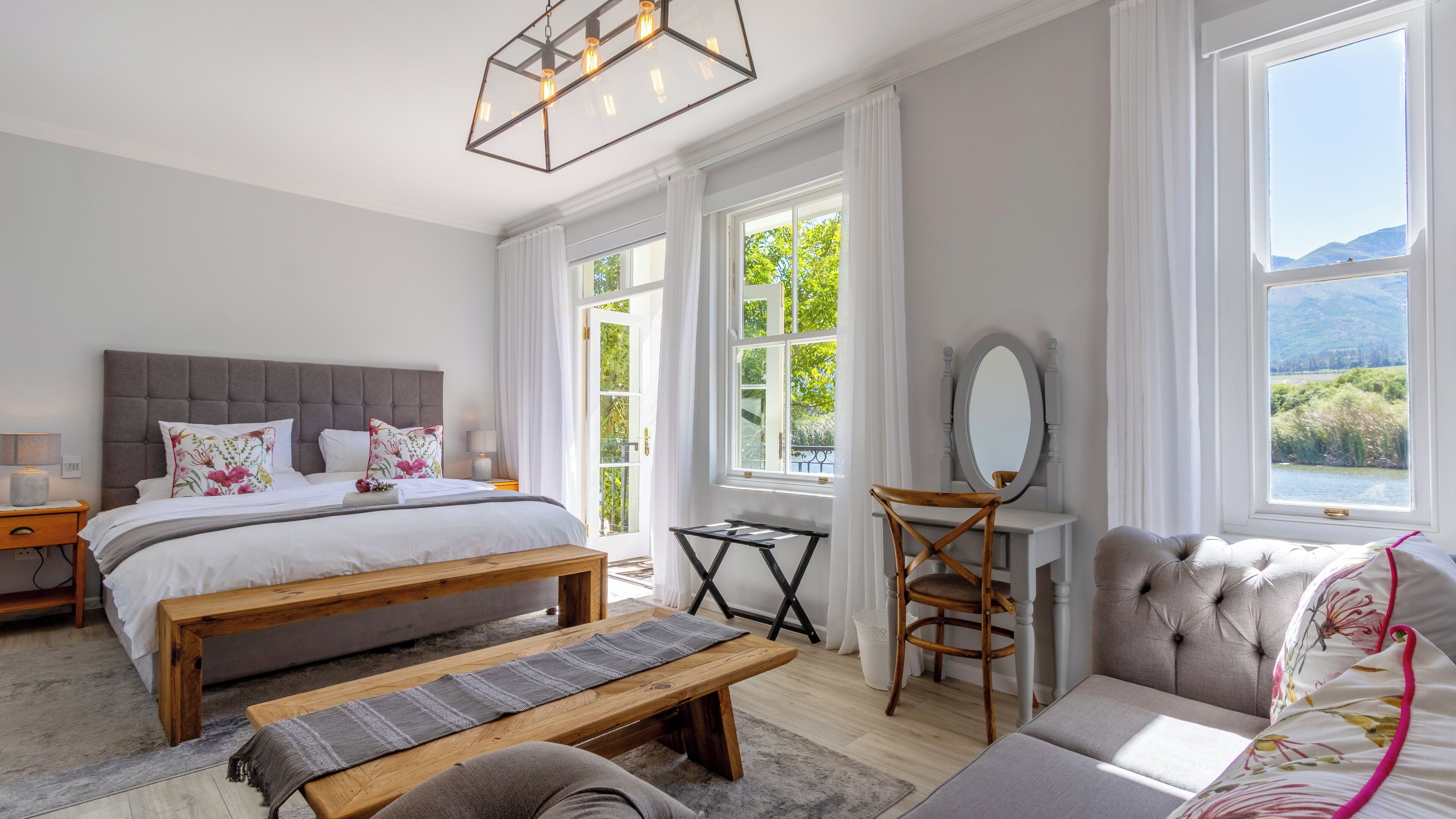 Ein Schlafzimmer mit einem großen Bett, einer hölzernen Bank, einem Schreibtisch mit Stuhl und einem Sofa.