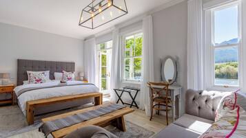 Un dormitorio con una cama grande, un banco de madera, un escritorio con silla y un sofá.