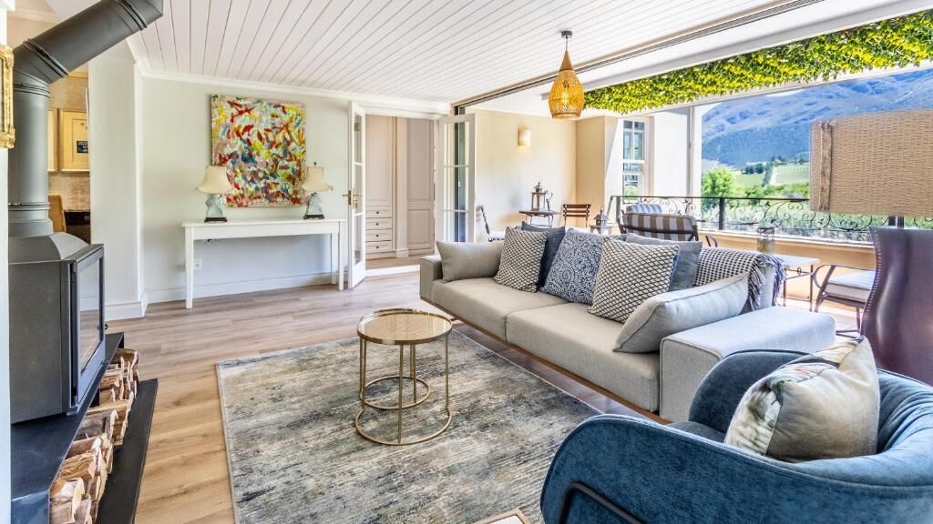 A modern living room with a sofa, a round coffee table, and a view of the outdoors.