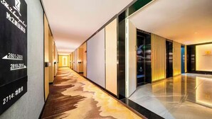 A hotel corridor with a patterned carpet, a reception desk, and a modern interior design. - Z Holiday Hotel (Chengdu)
