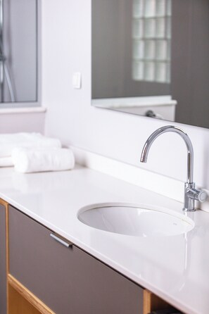 Une salle de bain moderne avec un lavabo blanc, un robinet chromé et un grand miroir au-dessus du lavabo.