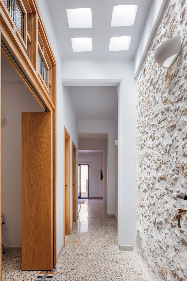 A hallway with wooden doors, a textured wall, and a ceiling with recessed lighting.