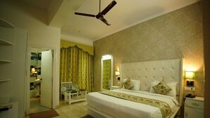 Habitación de hotel con una cama grande, un ventilador de techo, una mesita de noche y un buró.