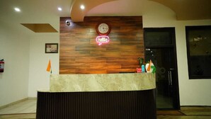 Una recepción con un panel de madera de fondo, un letrero de neón que dice 'hello' y un reloj.