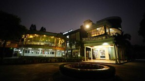 Un hotel de varios pisos con una sección central circular y un anexo de techo plano.