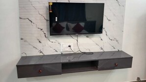 A flat-screen TV mounted on a marble wall with a power outlet below. - Royal Suites (Bangalore)