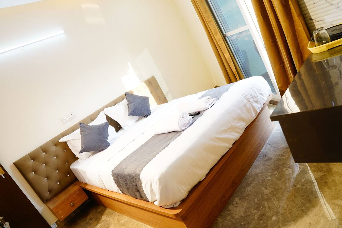 A neatly made bed with white and gray linens, a wooden headboard, and a bedside table with a lamp.