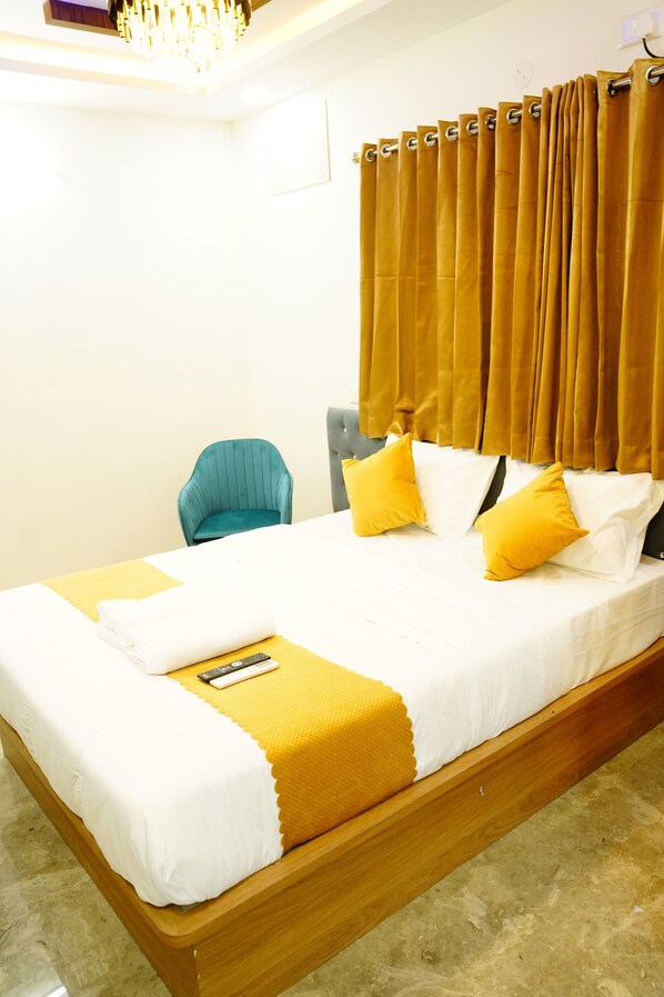A neatly made bed with white and yellow bedding, a remote control, and a yellow throw blanket. - Royal Suites (Bangalore)