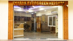 The entrance to Tharak Evergreen Heights with a glass door, a chandelier, and a sign above the door. - Royal Suites (Bangalore)