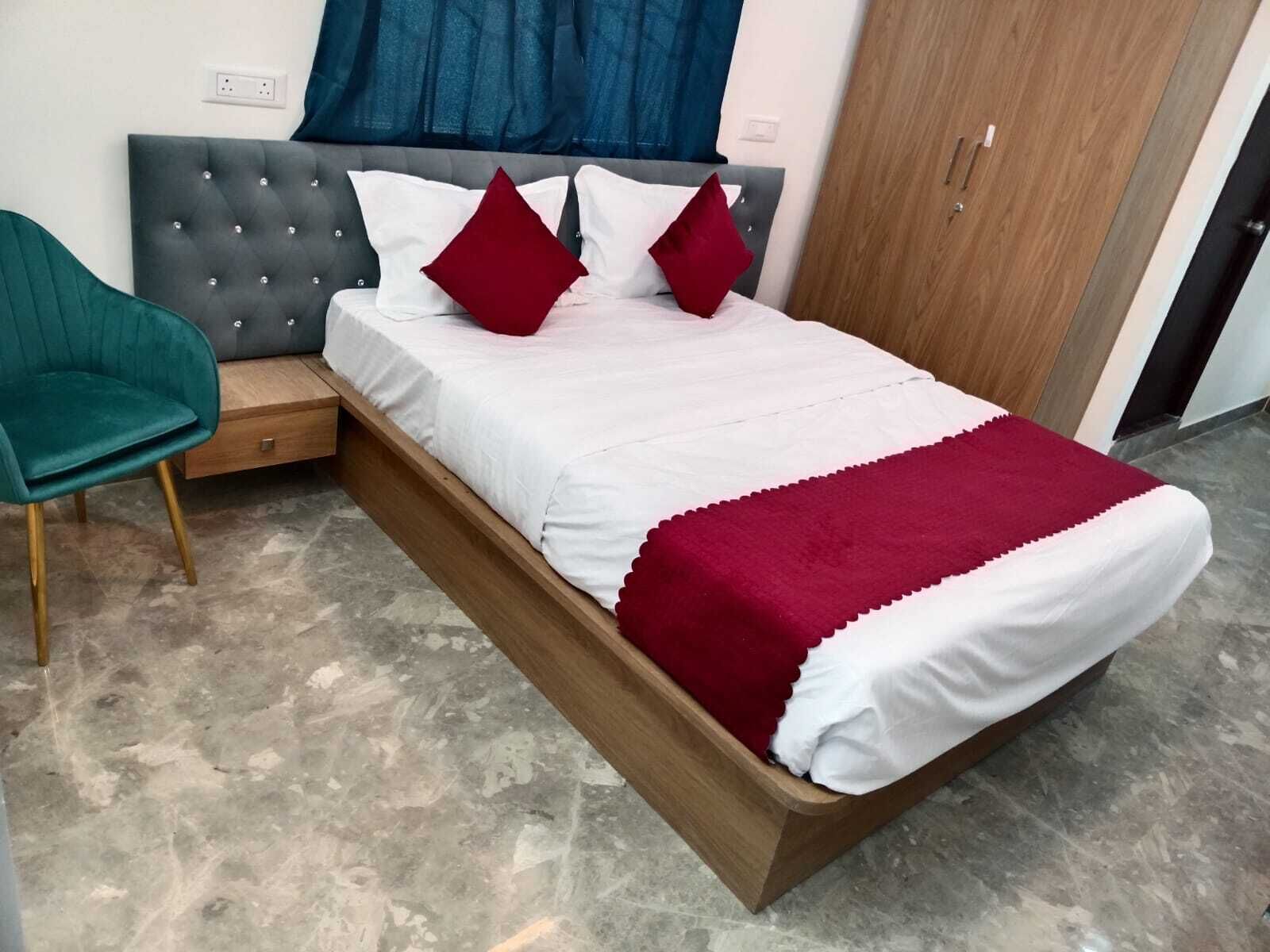 Ein Bett mit grau gepolstertem Kopfteil, weißer Bettwäsche und roten Kissen.