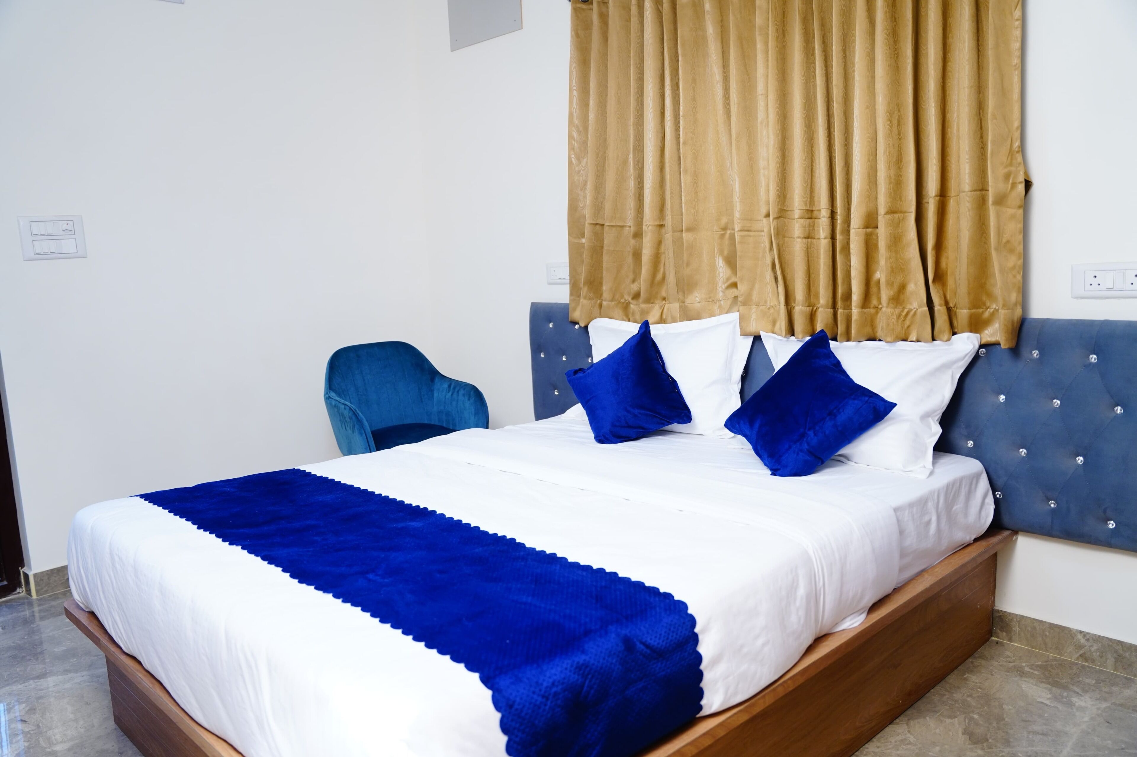 Un lit avec une couvre-lit bleue et blanche, une tête de lit bleue et un rideau marron.