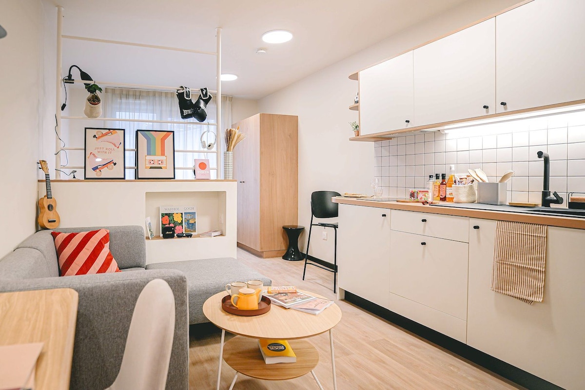 Una cocina moderna con armarios blancos, un grifo negro y una encimera de madera.