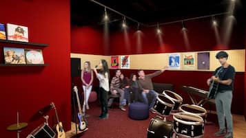 Ein Aufnahmestudio mit roter Wand, Musikinstrumenten und Postern.