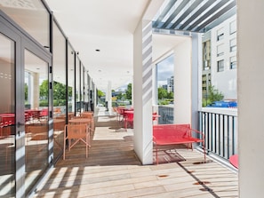 A covered outdoor seating area with tables and chairs, a wooden deck, and a view of buildings and trees. - Hife Bordeaux (Bordeaux)