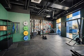 A gym with weight plates, a treadmill, and a wall with colorful artwork. - Hife Bordeaux  (Bordeaux)