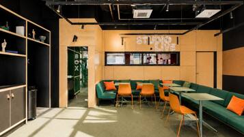 A modern interior with a long green sofa, orange chairs, and a 'STUDIO LIVE' sign.