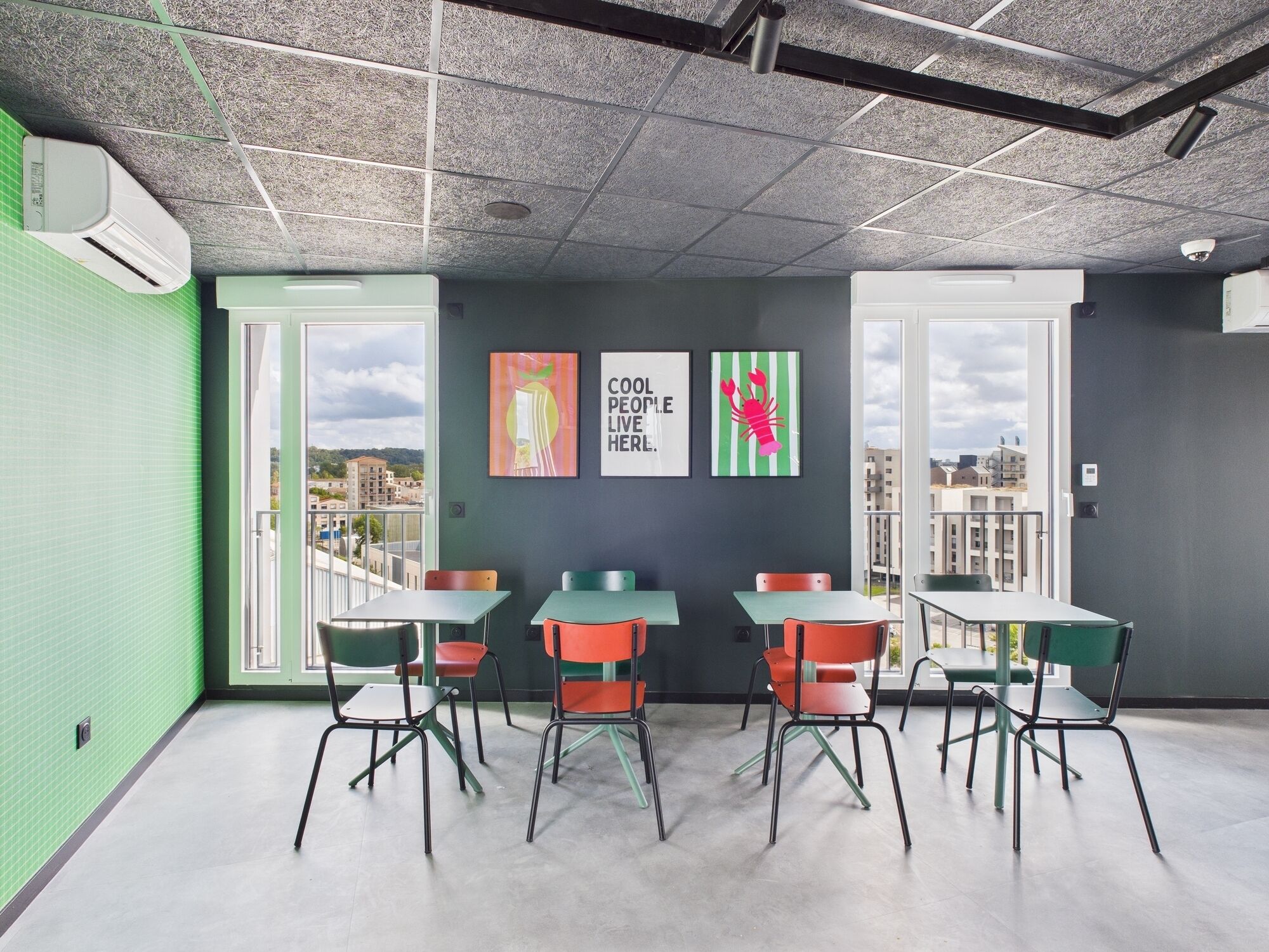 Una sala de reunions moderna amb grans finestres, parets verdes i obra d'art colorida.