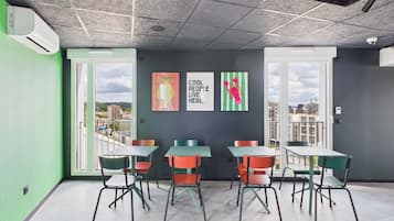 Una sala de reunions moderna amb grans finestres, parets verdes i obra d'art colorida.